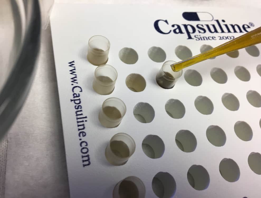 Filling capsules with infused oil for cannabis microdosing.