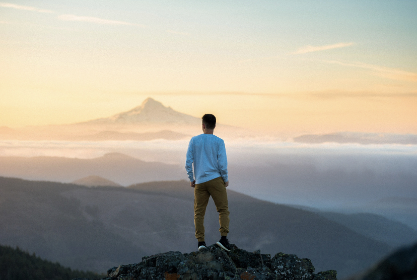 A man on top of a mountain looking out at the horizon.